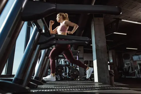 Mujer corriendo en una cinta de correr en un gimnasio moderno.